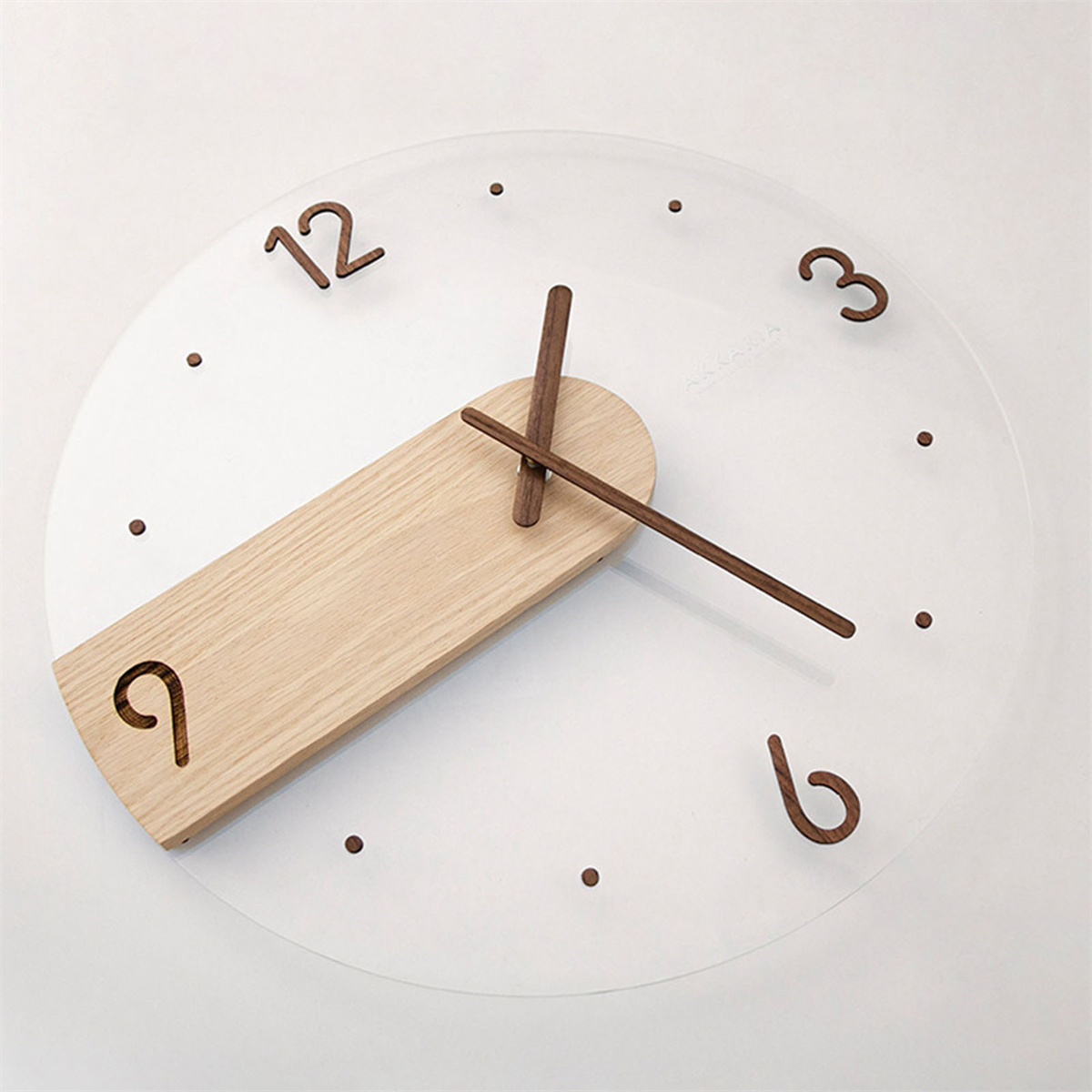Eine runde Uhr mit Holzzeigern und Zahlen auf einem klaren Zifferblatt. Weißer Hintergrund.