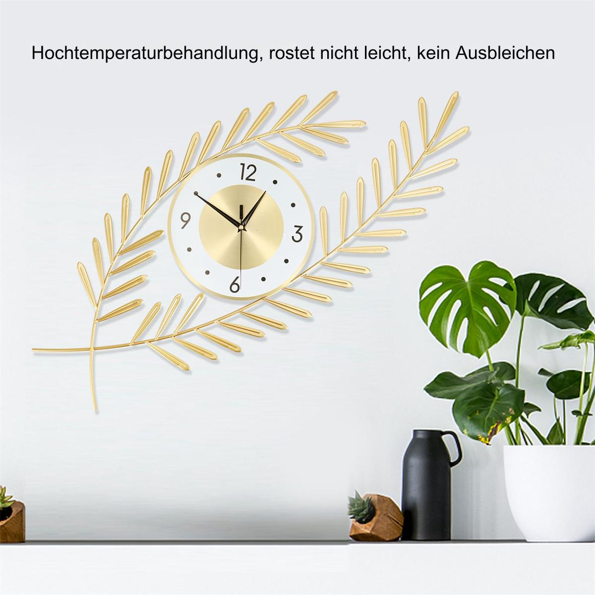 Goldene Wanduhr mit Blättern, im Hintergrund eine weiße Wand und grüne Pflanzen.