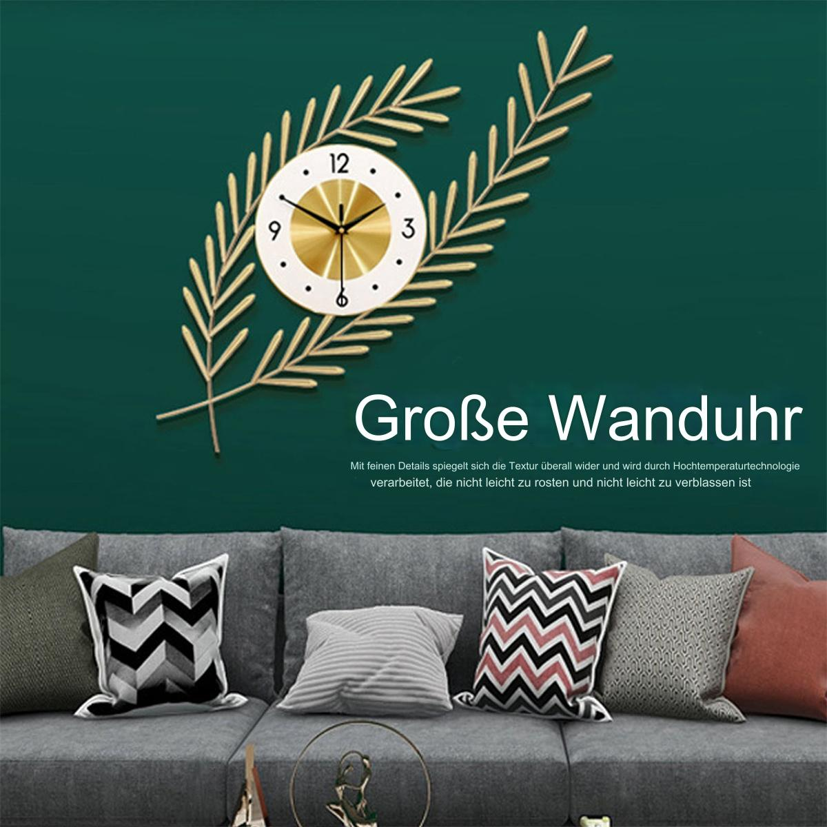 Eine Wanduhr an grüner Wand mit goldenen Blättern und einem Sofa mit Kissen. Die Uhr hat 12, 3, 6 und 9.