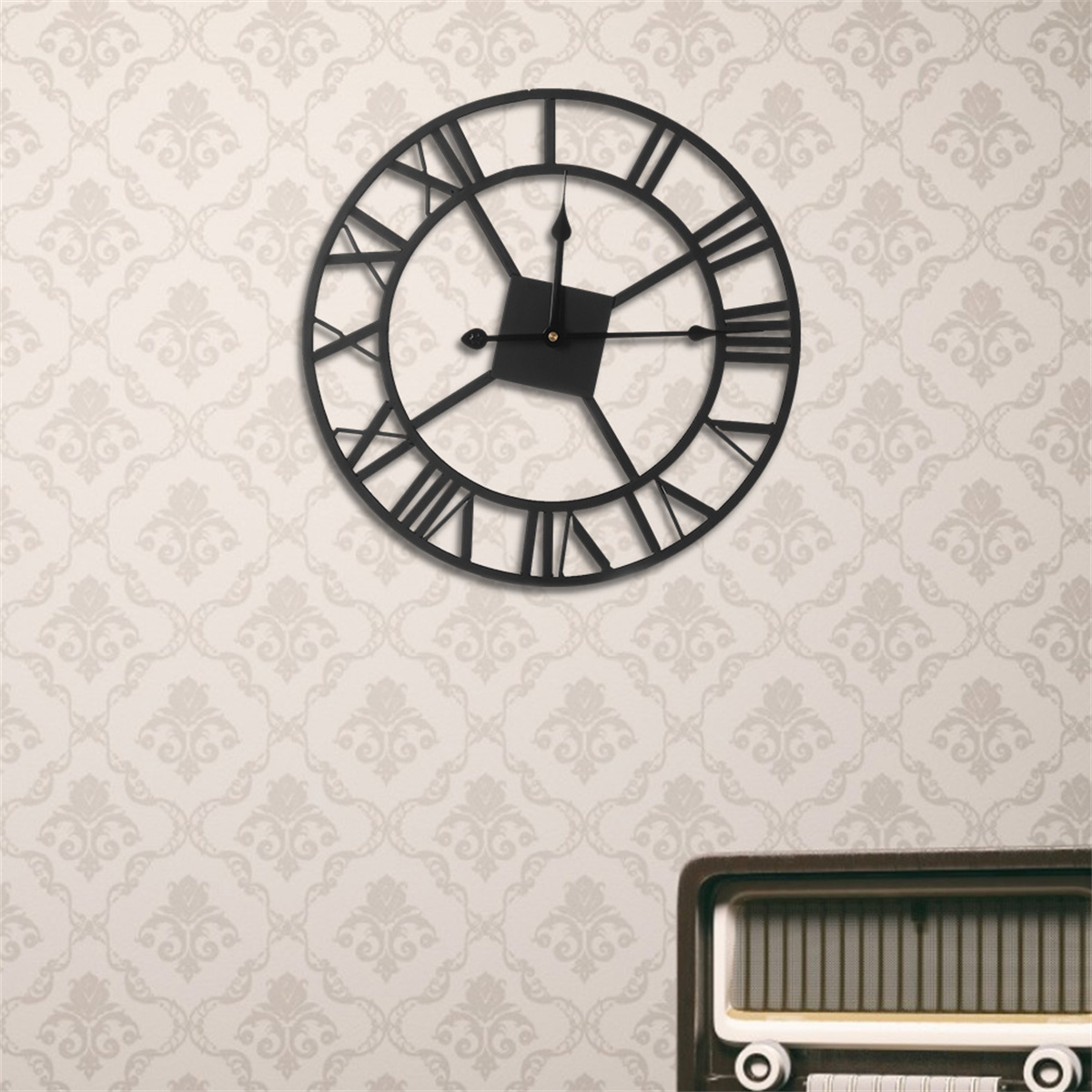 Eine schwarze, runde Wanduhr mit römischen Ziffern. Die Uhr befindet sich an einer gemusterten Wand. Darunter befindet sich ein Radio.