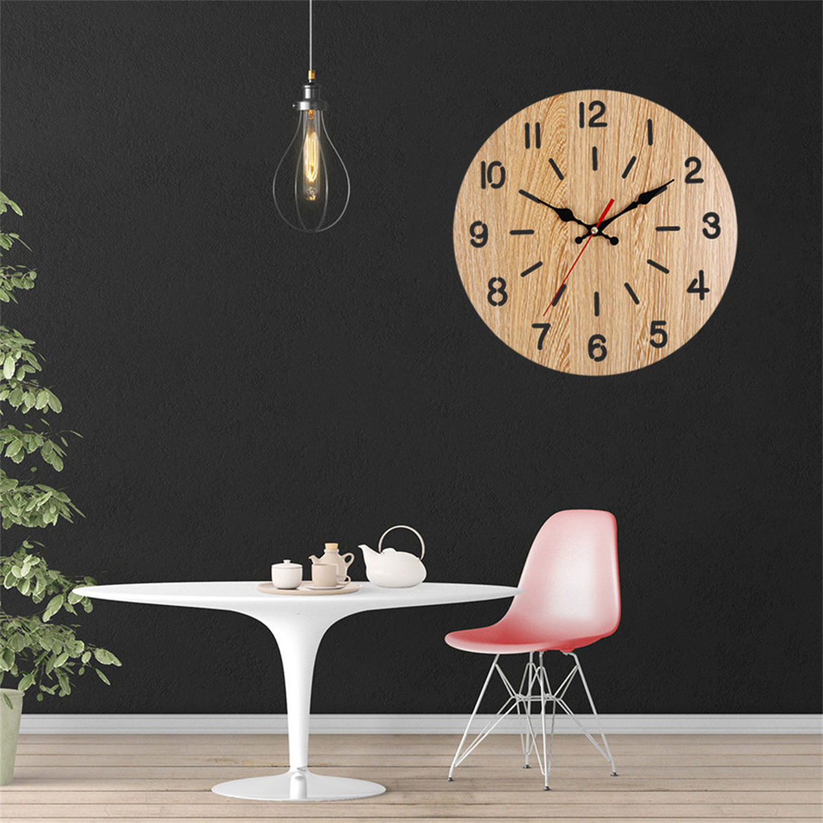 Runde Holzuhr an einer Wand. Tisch mit Teekanne und Tassen, rosa Stuhl im Vordergrund.