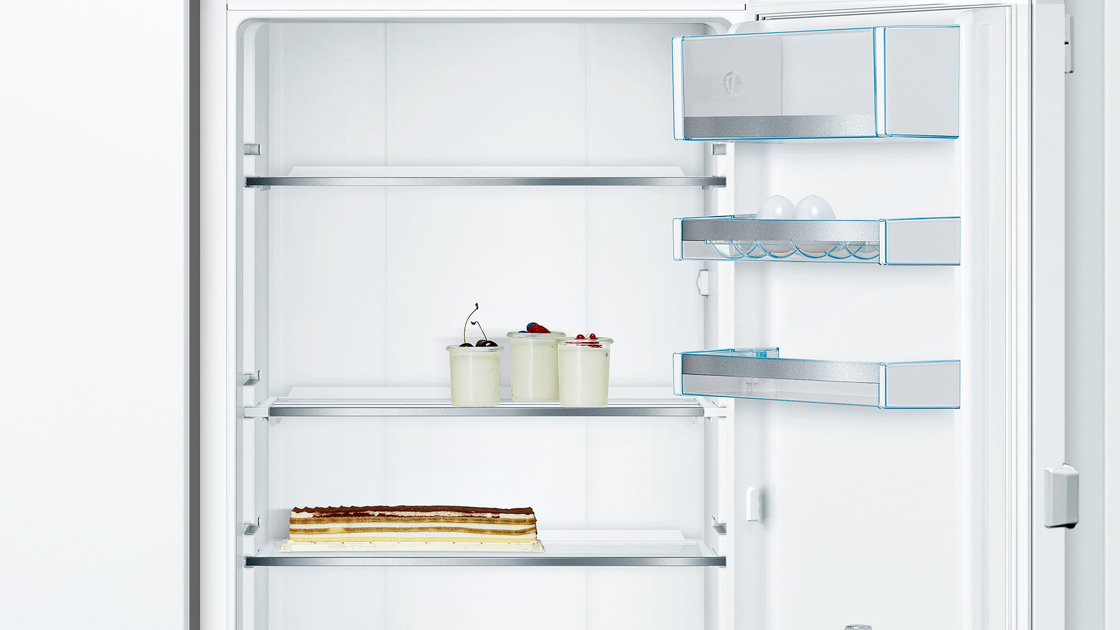 Kühlschrankinnenraum mit Essen: Kuchen, Joghurt und Kirschen.