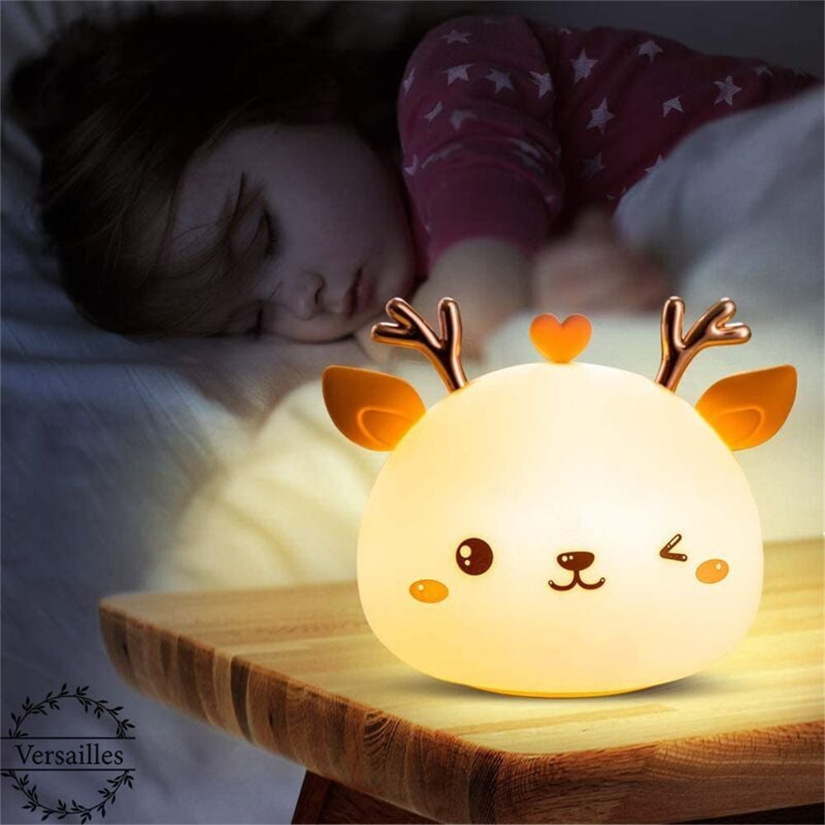 Ein rehförmiges Nachtlicht beleuchtet ein schlafendes Kind. Es steht auf einem Holztisch. Die Lampe ist weiß und gelb.