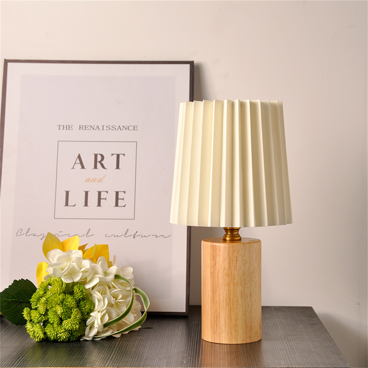Holzlampe mit beigem Lampenschirm, Blumen und einem gerahmten Kunstdruck.