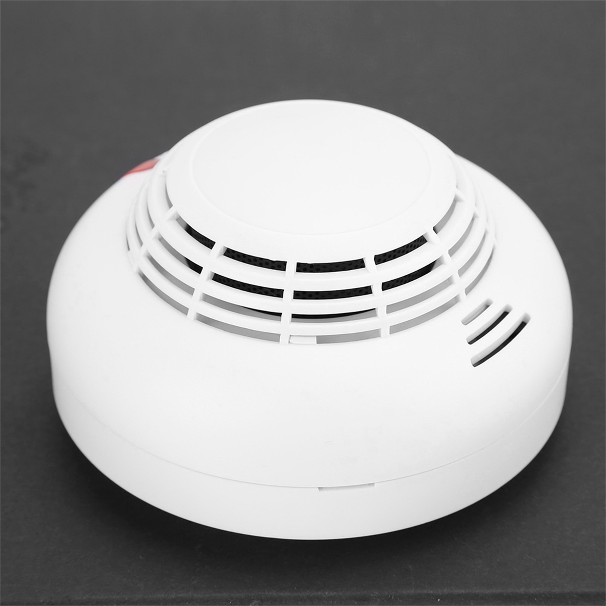 Weißer Rauchmelder mit rundem Design. Er hat ein Gitter und ein rotes Licht.