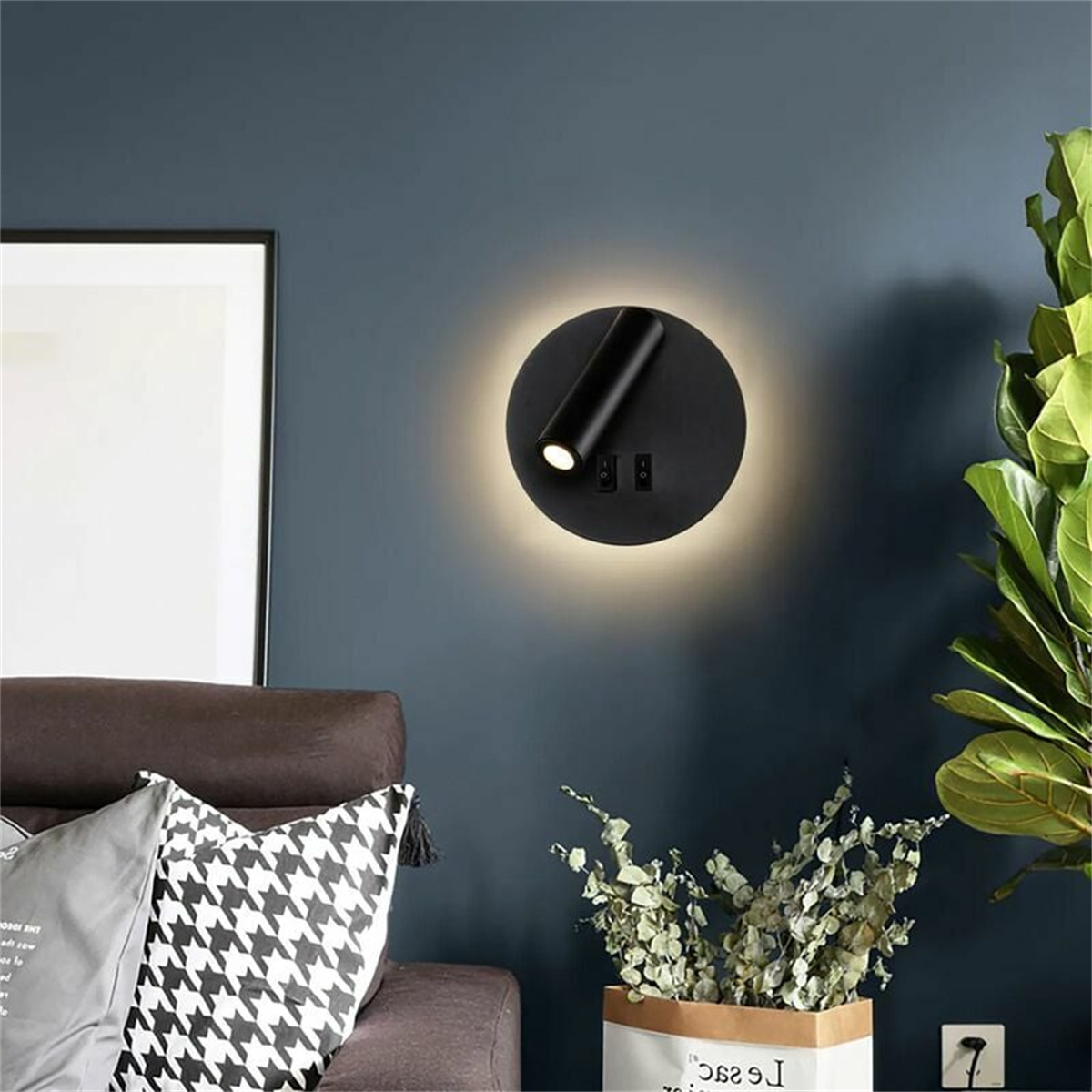 Schwarze Wandlampe, runde Form mit Licht und zwei Schaltern, an einer blauen Wand.