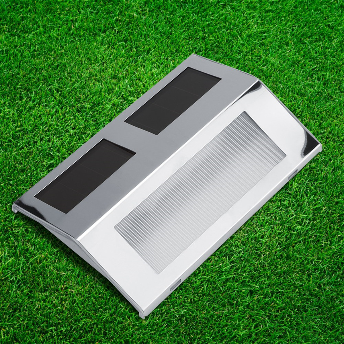 Eine silberne Solarleuchte auf grünem Gras mit zwei schwarzen Solarpanels.