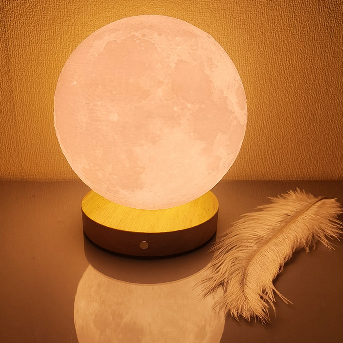 Eine mondförmige Lampe auf einem Holzsockel, mit einer Feder auf einer reflektierenden Oberfläche.