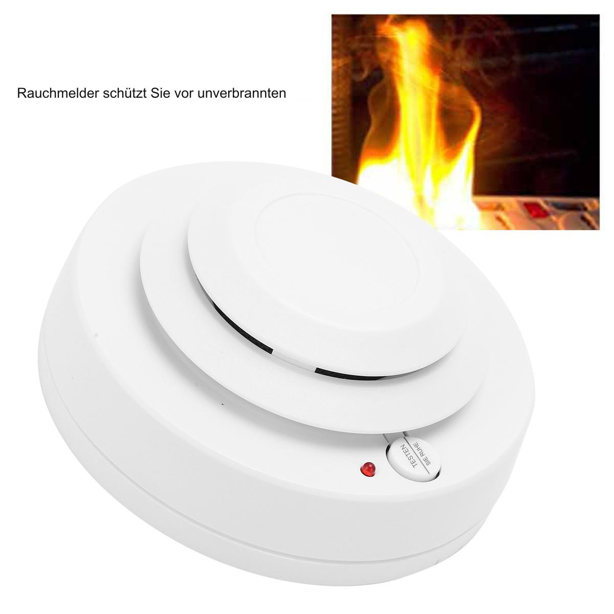 Weißer Rauchmelder mit Feuer im Hintergrund. Auf dem Knopf steht 'Test'. Text auf Deutsch.