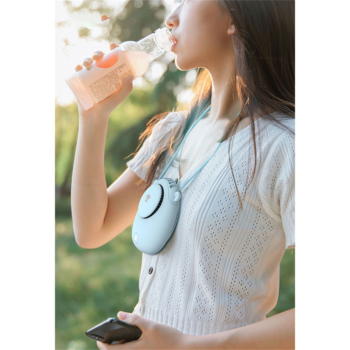 Eine Frau trinkt aus einer Flasche, während sie einen Nackenventilator trägt.
