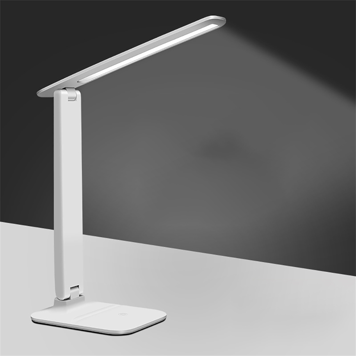 Weiße, verstellbare Schreibtischlampe. Die Lampe leuchtet und wirft einen Lichtstrahl auf eine graue Oberfläche.