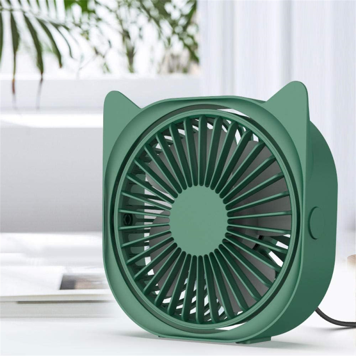 Ein grüner Ventilator mit Katzenohren auf einer weißen Oberfläche. Der Ventilator hat viele Flügel und eine runde Mitte.
