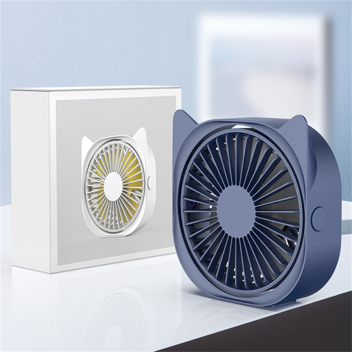 Blauer fächerförmiger Ventilator mit Katzenform und einer Box auf weißer Oberfläche.