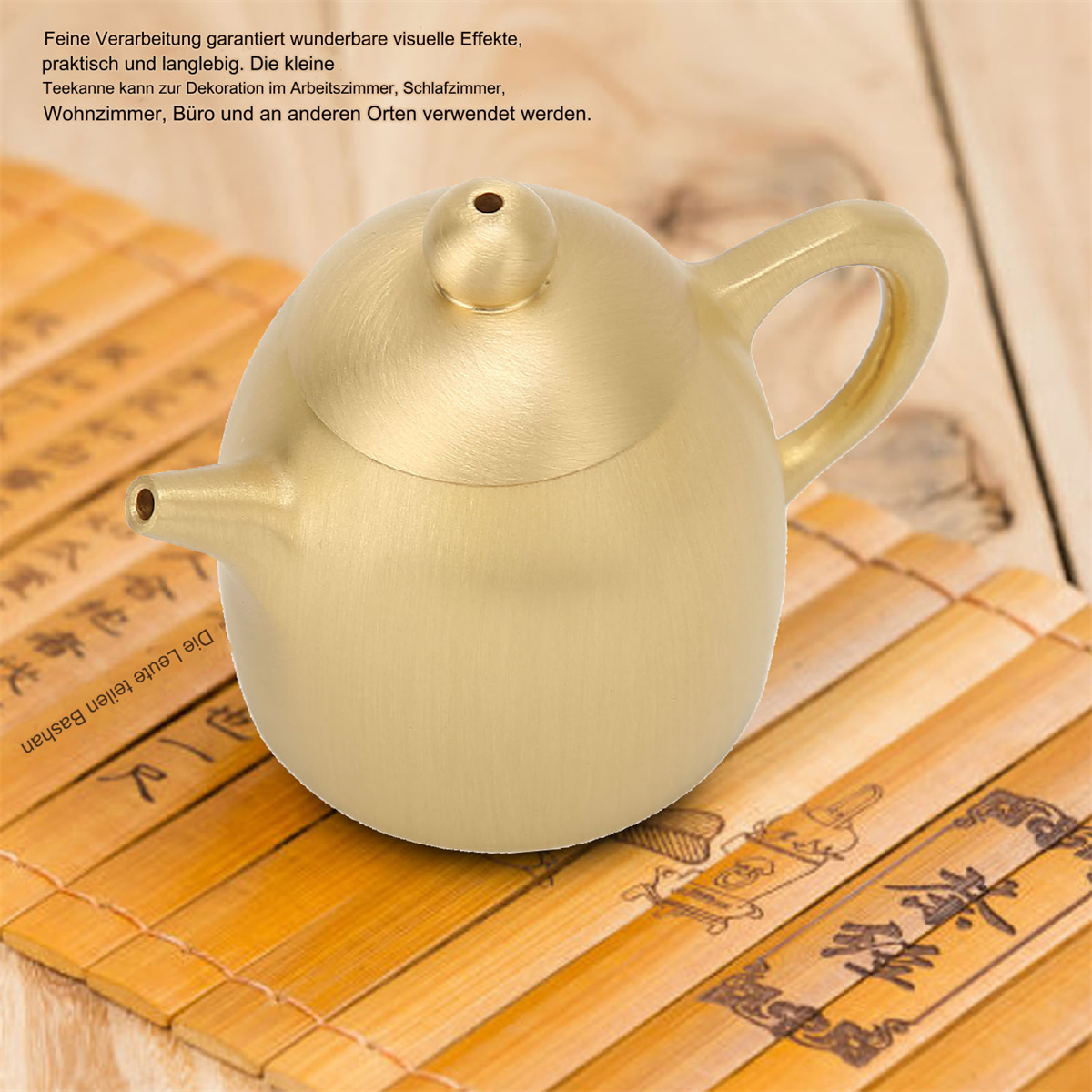 Goldene Teekanne auf Bambusmatte. Text im Hintergrund. Goldene Farbe. Teekanne mit Griff.