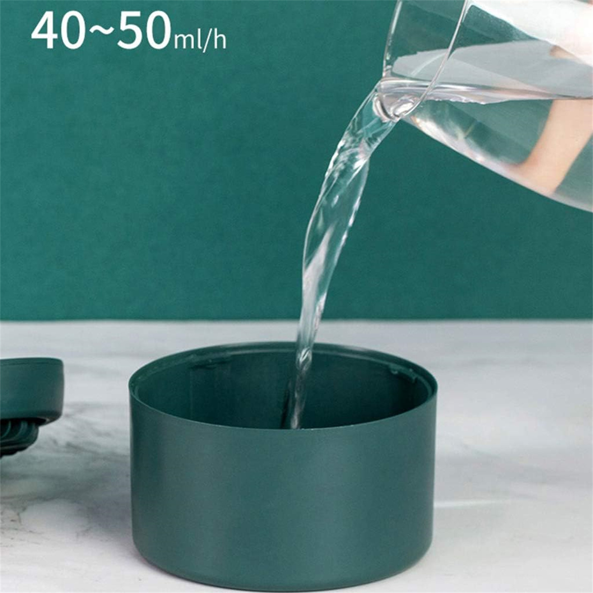 Wasser wird in einen dunkelgrünen Behälter gegossen. Der Behälter ist zylindrisch mit einem gebogenen Rand.