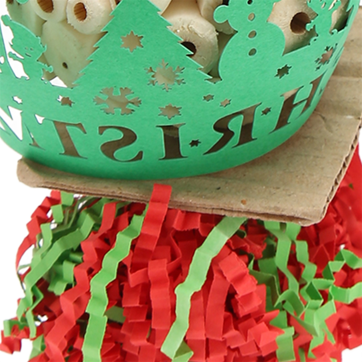 Grüner Weihnachtsbehälter mit weißen Gegenständen, auf einem braunen Kartonsockel, rotes und grünes geschreddertes Papier.