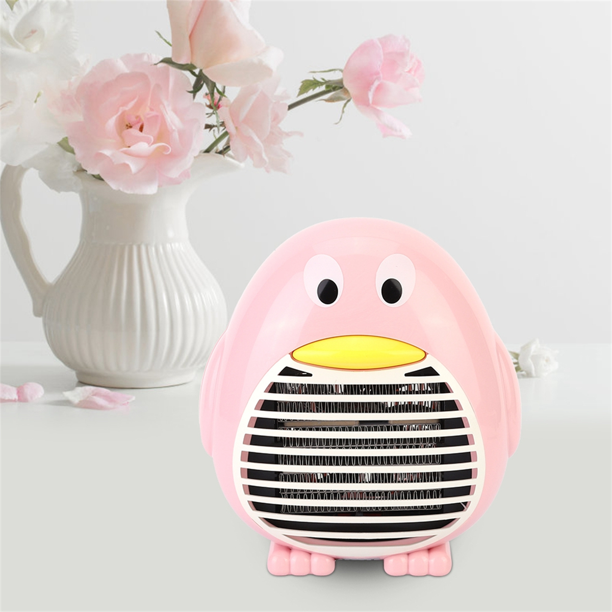 Ein rosa pinguinförmiger Heizlüfter mit weißer Vase und Blumen.