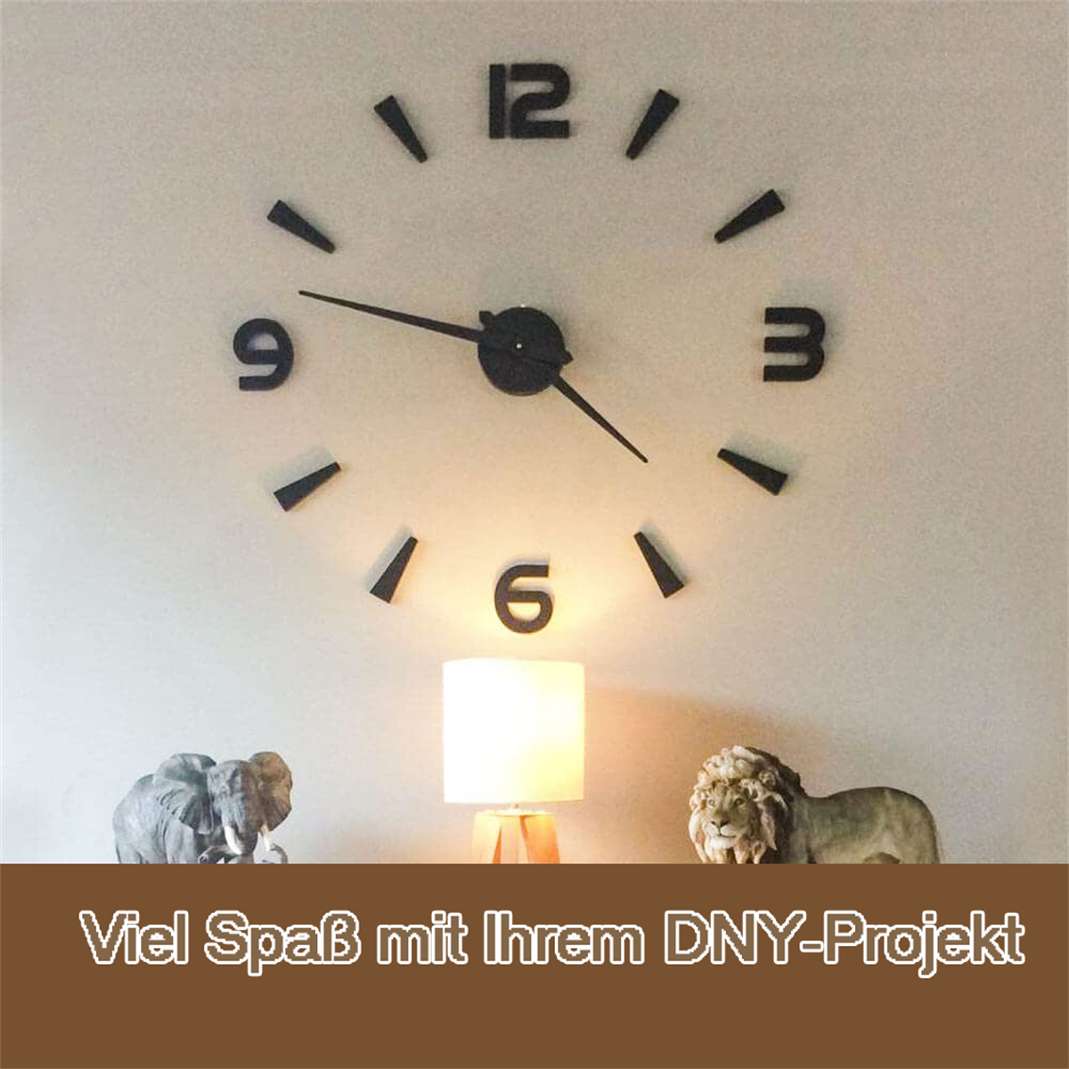 Große Wanduhr mit schwarzen Zahlen und Zeigern. Der Hintergrund ist eine neutrale Wand mit Dekoration.