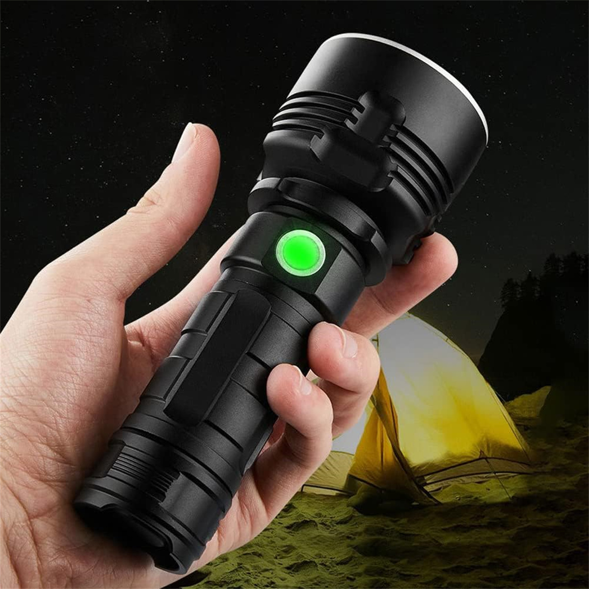 Hand hält eine schwarze Taschenlampe mit grünem Knopf, vor einem Zelt bei Nacht.