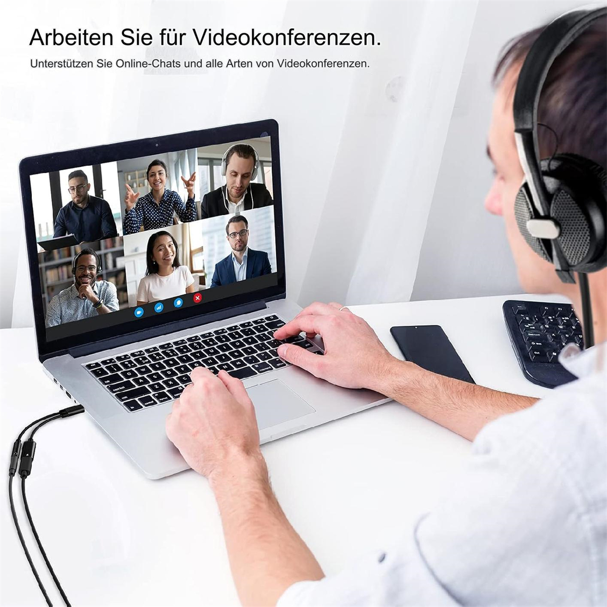 Ein Laptop, der eine Videokonferenz mit sechs Personen anzeigt. Eine Person mit Kopfhörern nutzt den Laptop.