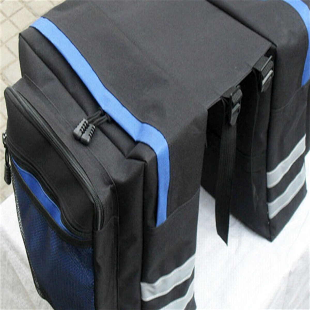 Eine schwarze Fahrradtasche mit blauen Akzenten und reflektierenden Streifen, mit Reißverschluss.