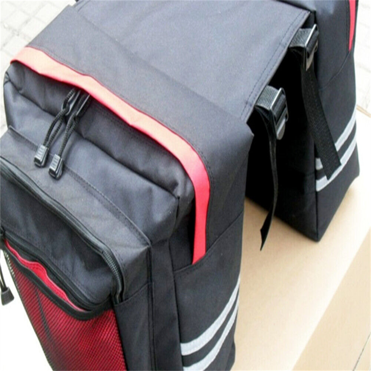 Schwarze Fahrradtaschen mit roten Akzenten und reflektierenden Streifen. Die Taschen sind befestigt.