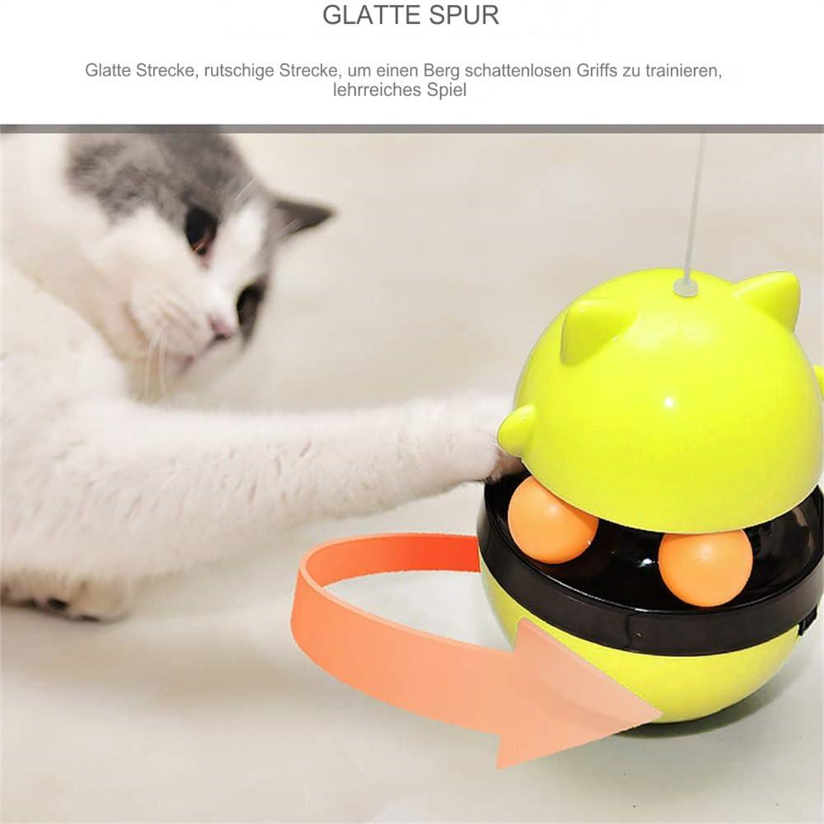 Eine Katze spielt mit einem gelben Spielzeug mit orangefarbenen Kugeln. Ein orangefarbener Pfeil zeigt auf das Spielzeug.
