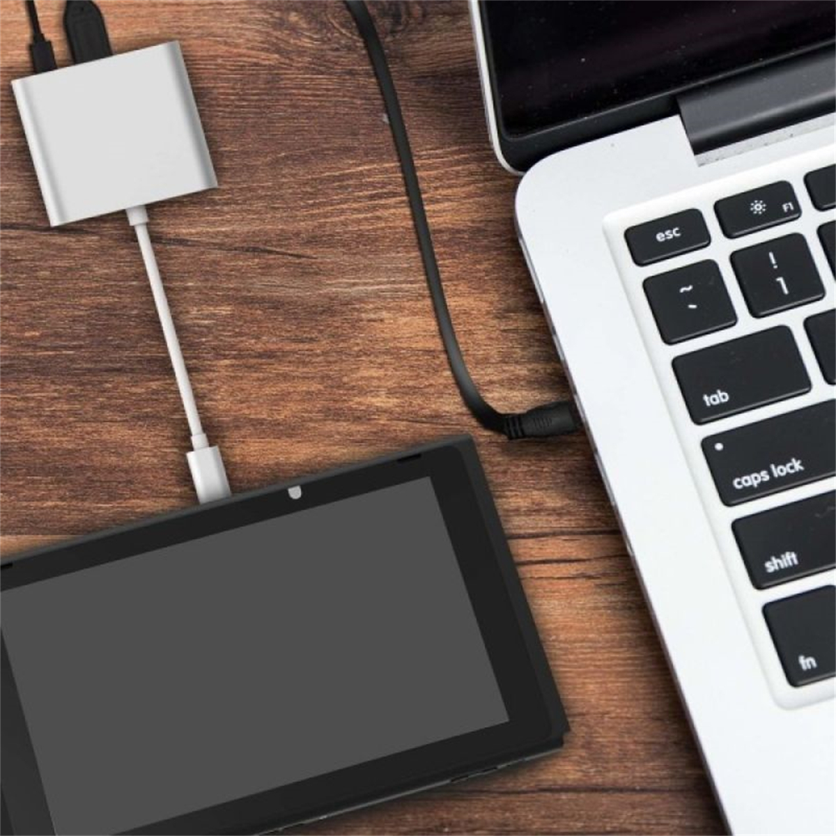 Ein Laptop, der mit einem Tablet und einem USB-Hub auf einer Holzoberfläche verbunden ist.