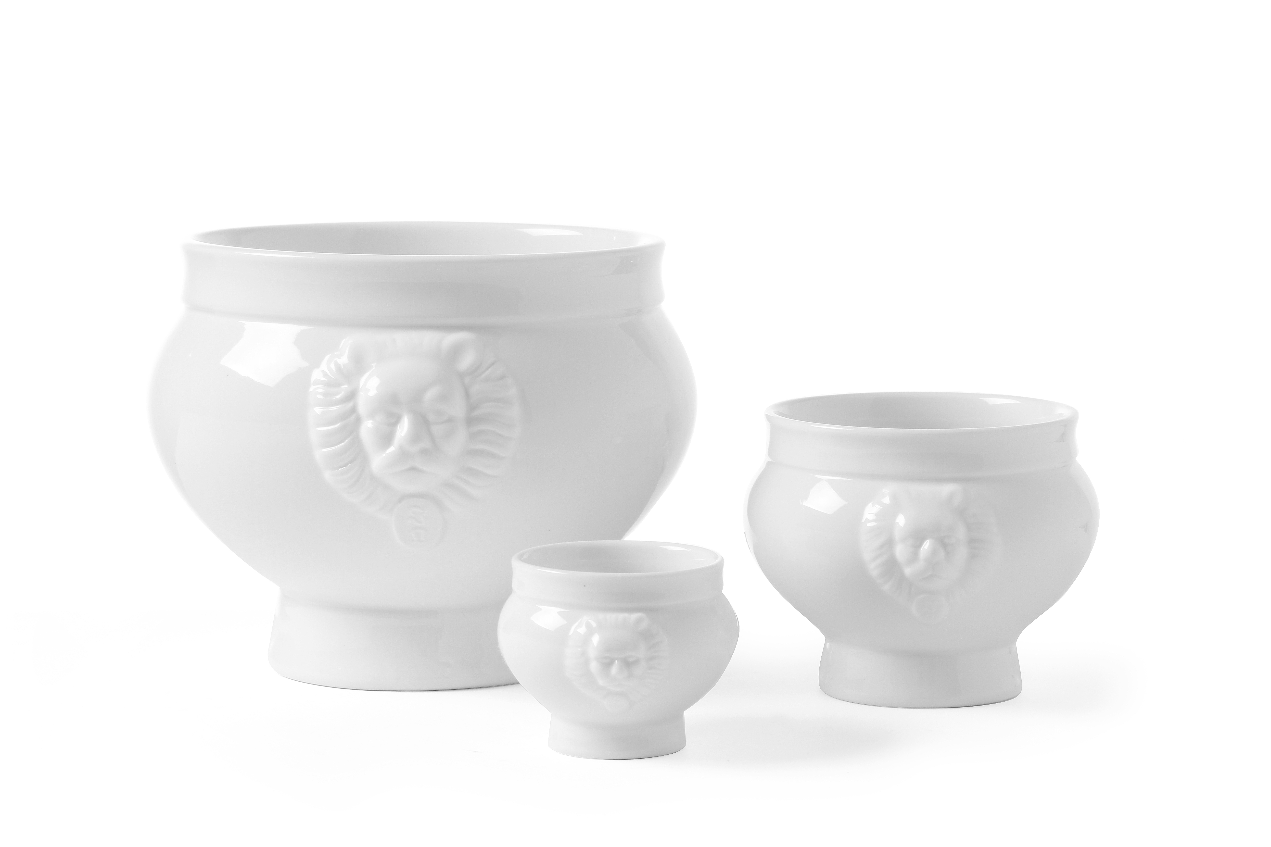 Tre vasi in ceramica bianca con rilievi a testa di leone, di diverse dimensioni, su bianco.