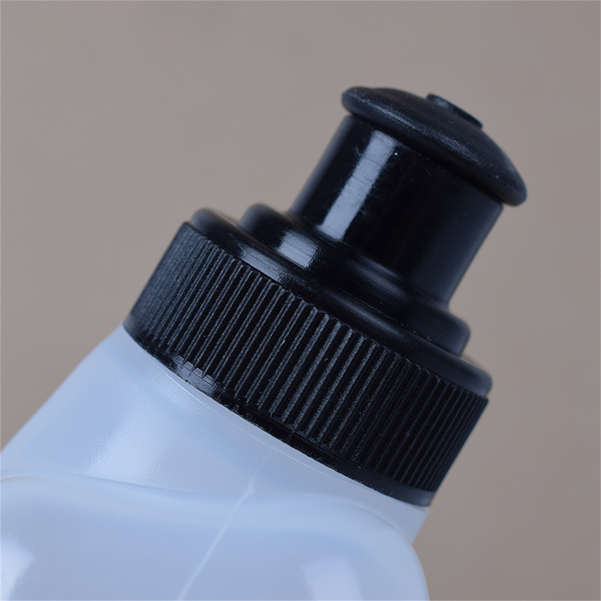 Nahaufnahme des schwarzen Verschlusses einer Wasserflasche mit geriffelter Griff.