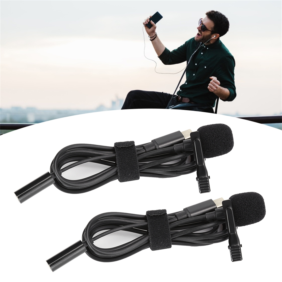 Zwei schwarze Mikrofone mit Kabel und Klemme. Im Hintergrund hält ein Mann ein Telefon.