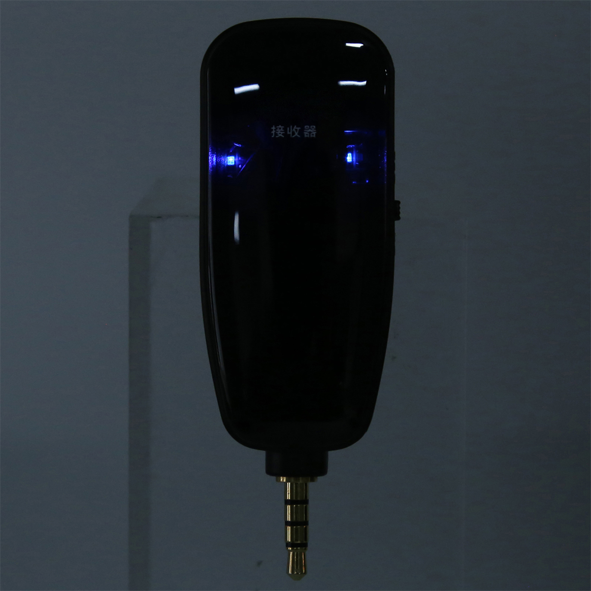 Ein schwarzer Mikrofonempfänger mit blauen Kontrollleuchten, mit 3,5-mm-Klinke unten.