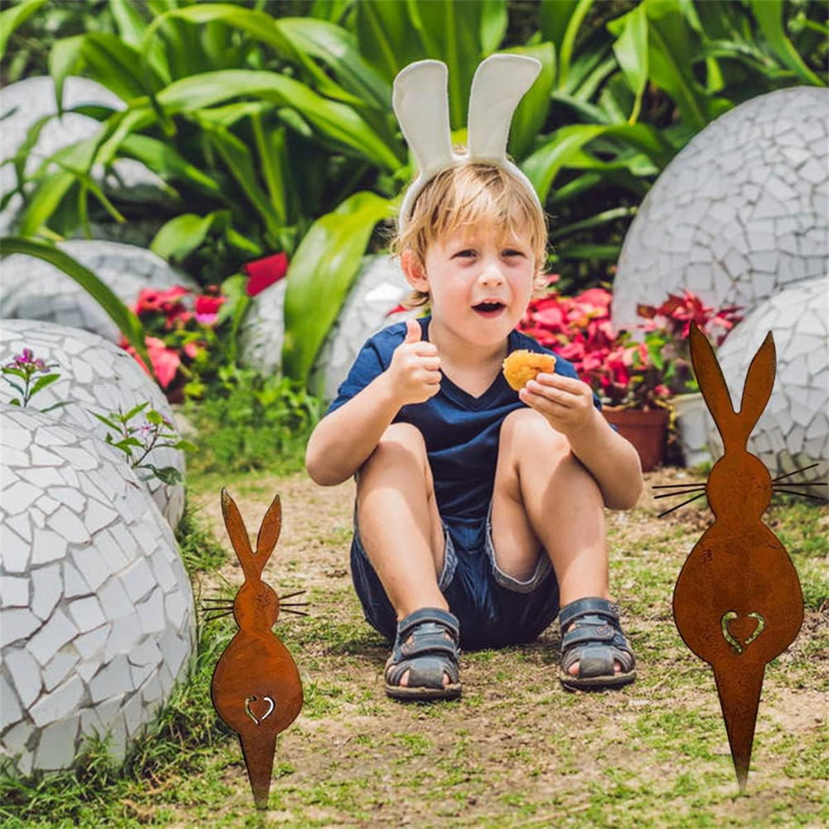 Ein Kind mit Hasenohren, das einen Imbiss hält, mit Hasenausschnitten vor einem Garten.