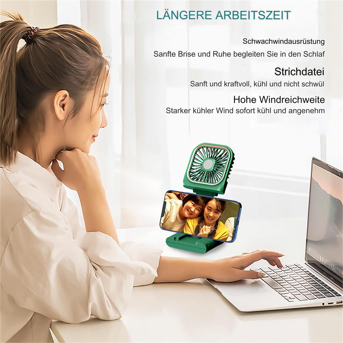 Frau benutzt Laptop mit Handy, das ein Foto anzeigt, und einem kleinen Ventilator, der auf das Handy bläst.