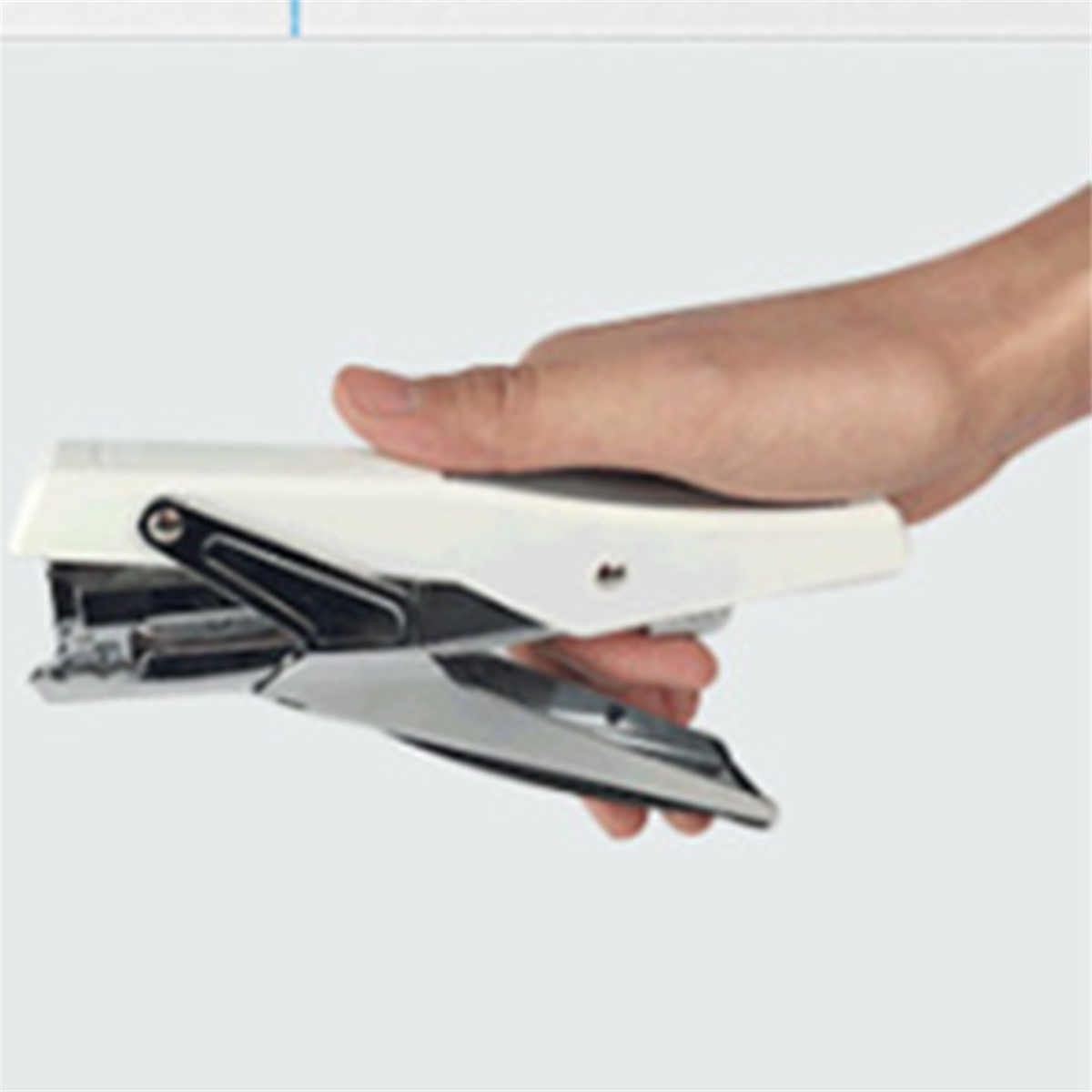 Hand hält einen weißen Tacker, silberner Mechanismus sichtbar. Der Hintergrund ist unscharf.