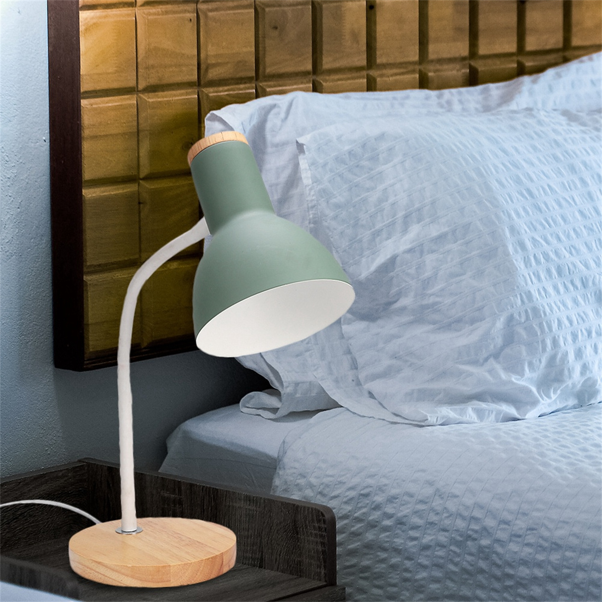Grüne und hölzerne Tischlampe auf einem Nachttisch neben einem Bett.