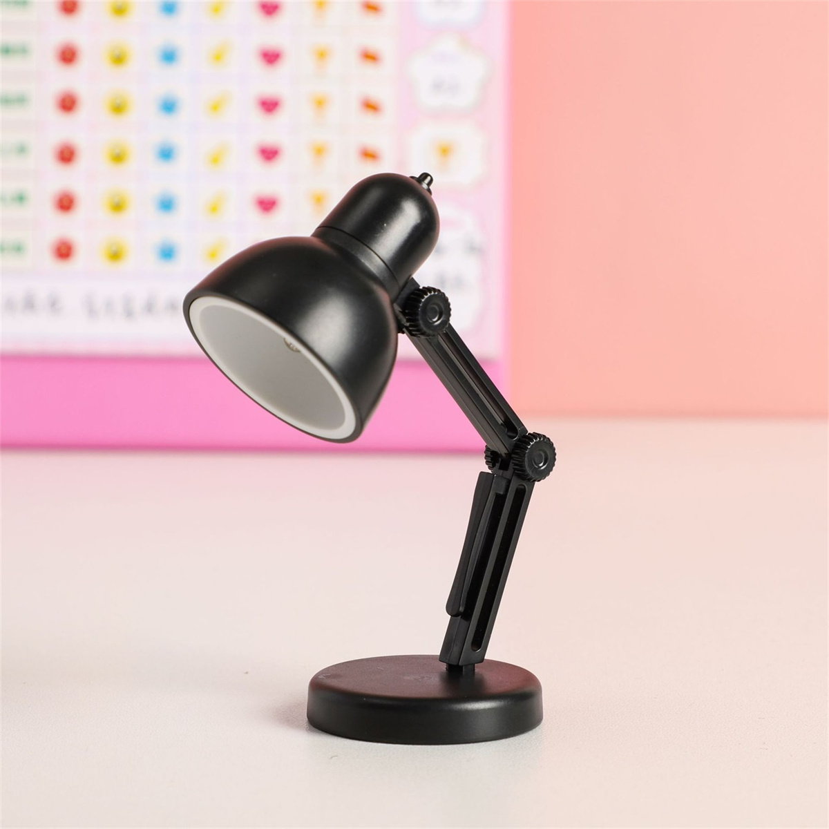 Eine schwarze Schreibtischlampe mit verstellbarem Arm auf weißer Oberfläche.