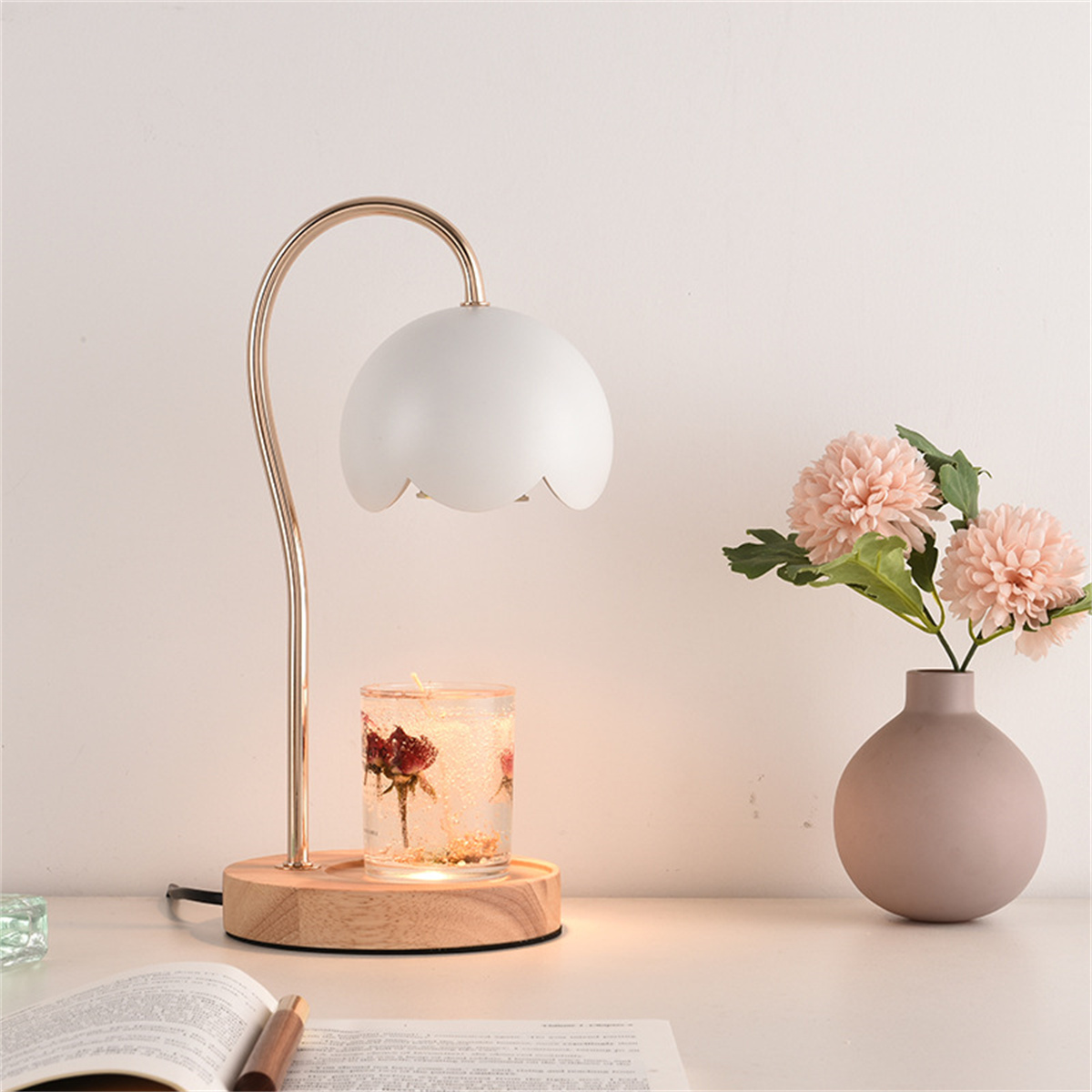 Weiße und goldene Lampe mit floralem Design und Kerzenhalter auf Holzsockel.