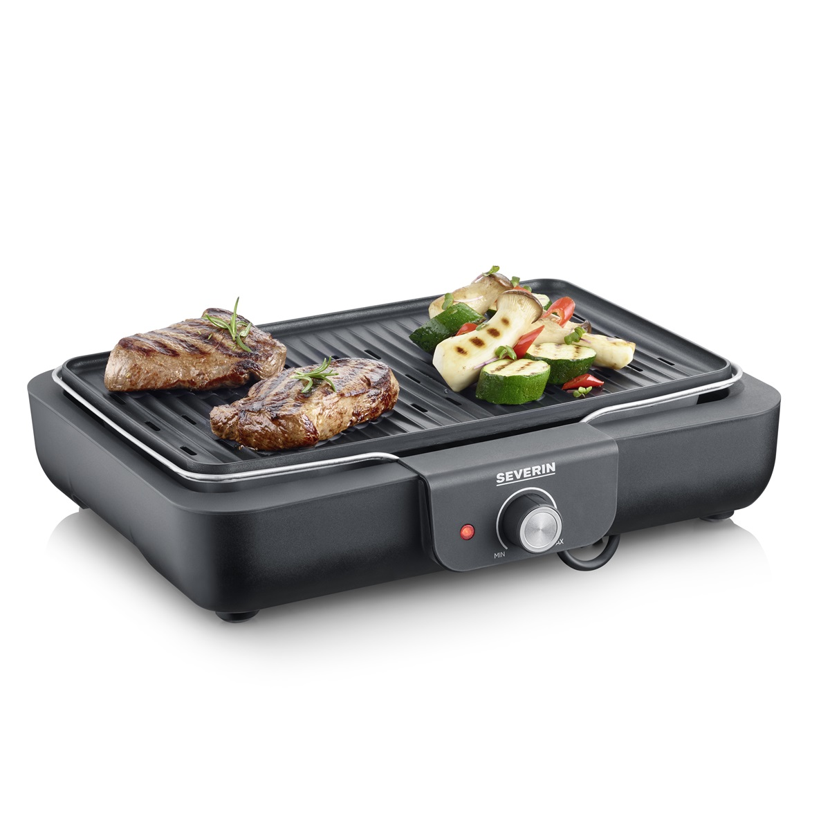 A black electric grill with steaks and vegetables cooking on it, set against a white background.