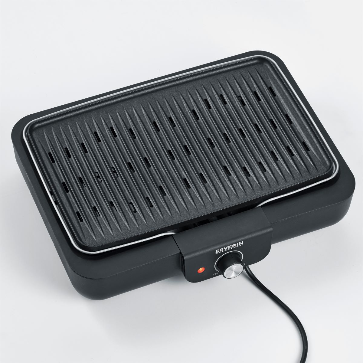 A black grill with a heating element and temperature control knob. It sits on a white surface.
