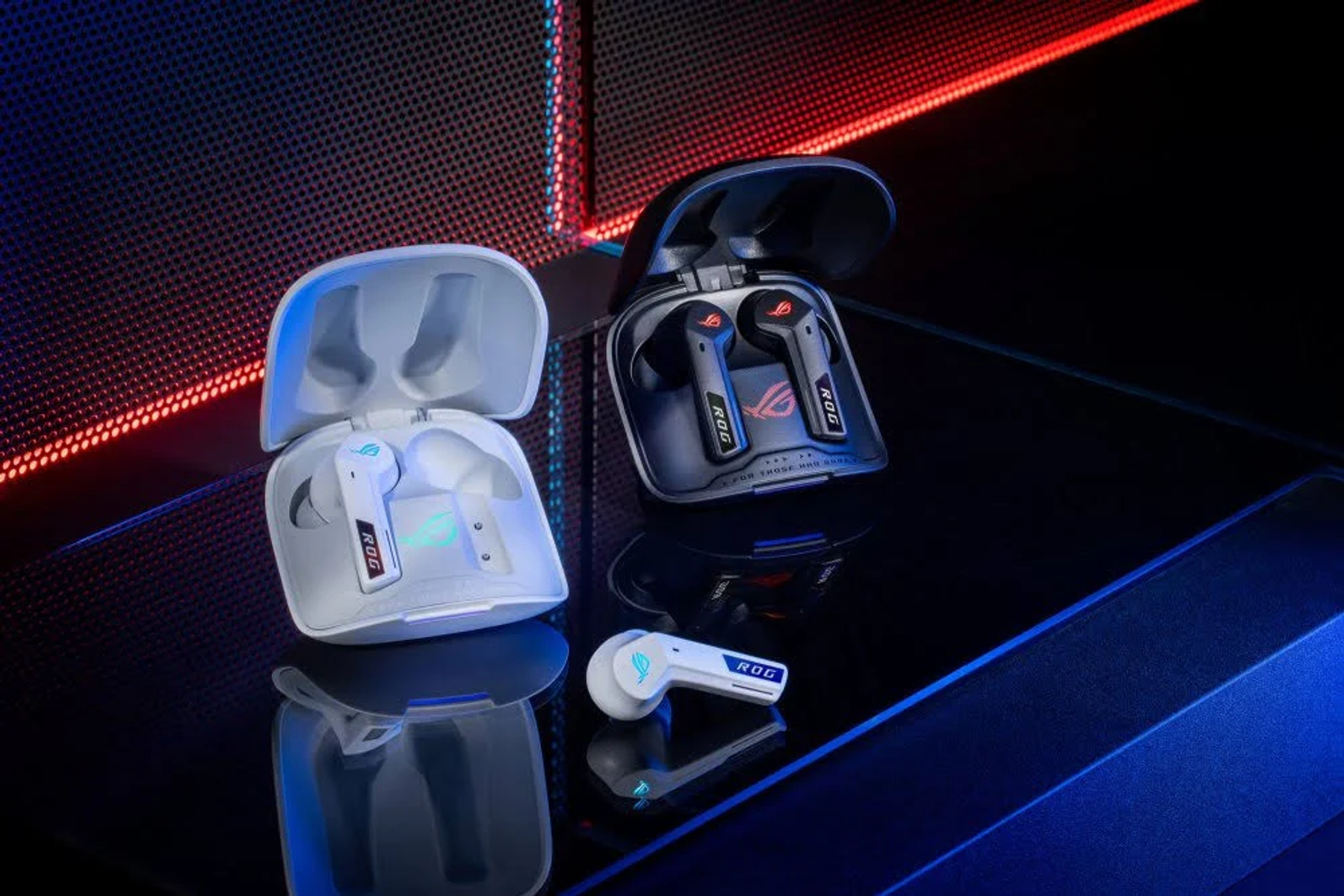 Białe i czarne słuchawki ROG z etui ładującymi na szklanej powierzchni.