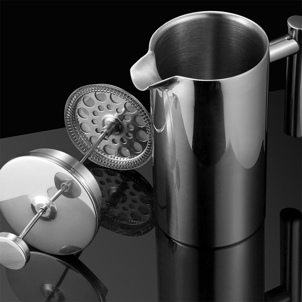 Eine French Press aus Edelstahl mit zerlegten Teilen. Ein schwarzer Hintergrund reflektiert die Objekte.