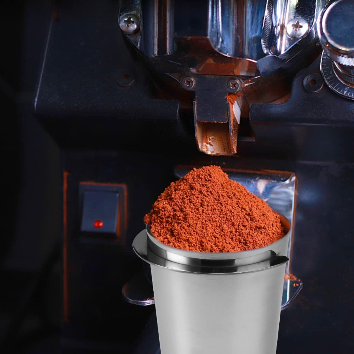 Ein Edelstahlbehälter mit Kaffeepulver wird vor einer Espressomaschine befüllt.