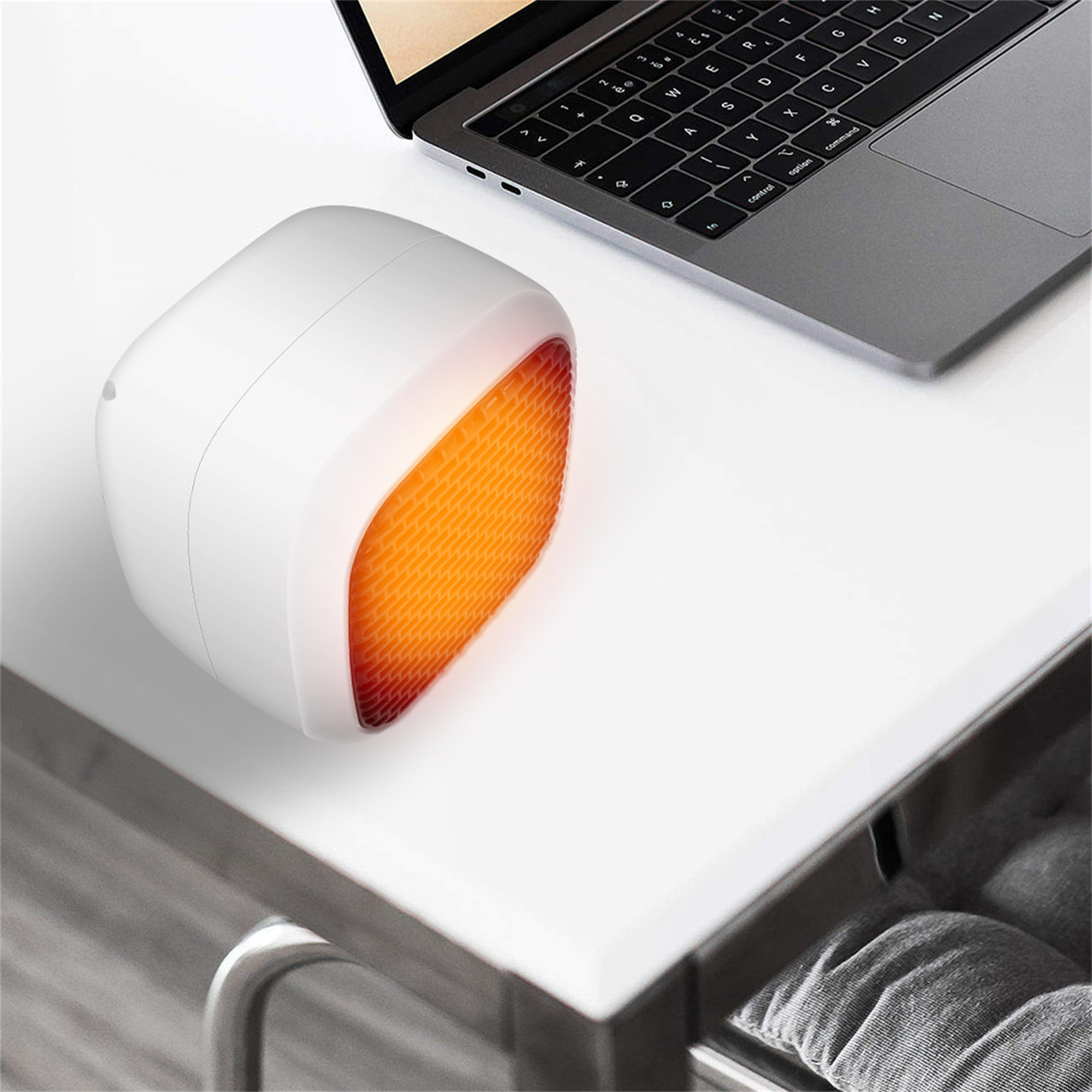 Ein weißer Schreibtischheizer mit einer orangefarbenen Wabe, mit einem Laptop auf einem weißen Schreibtisch.