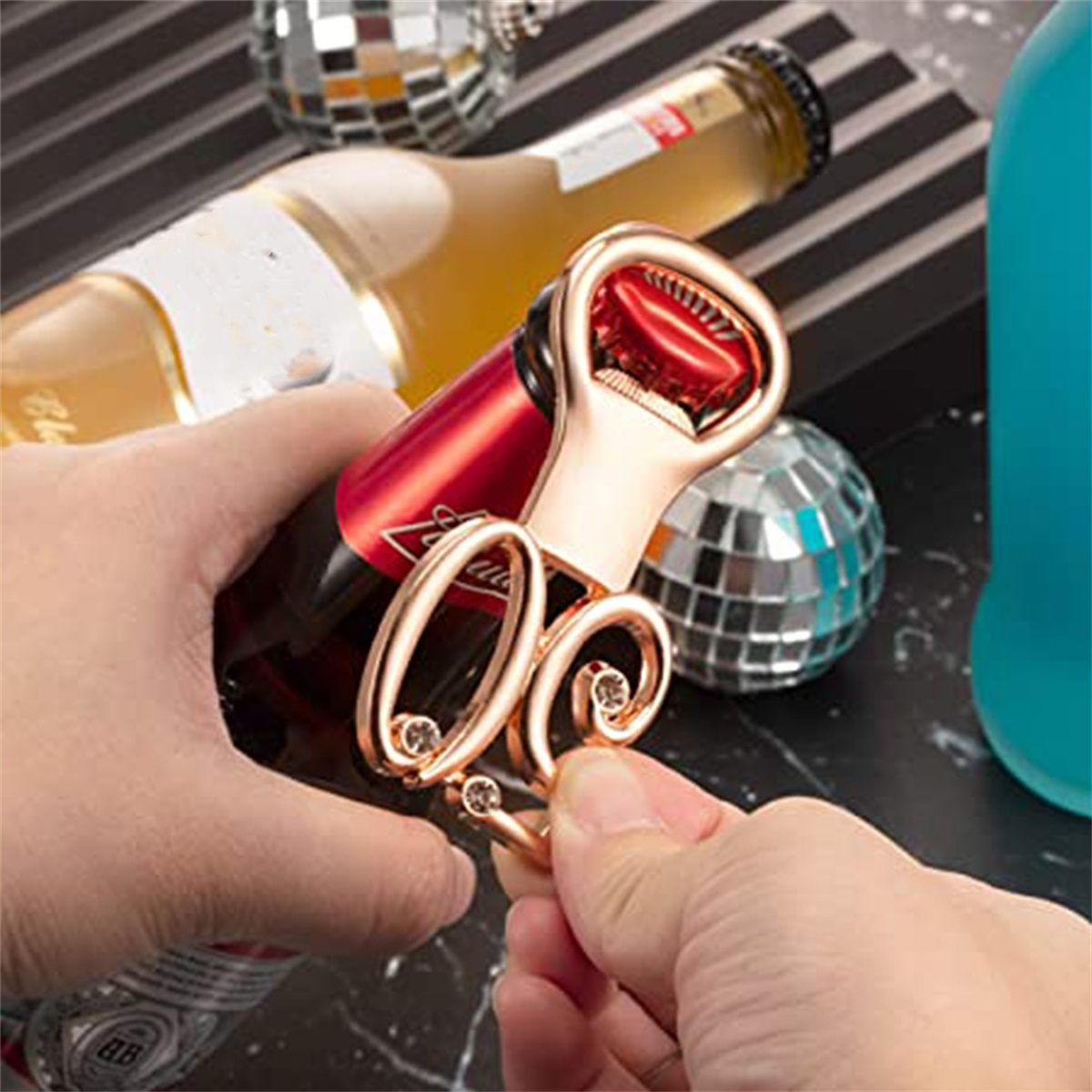 Ein goldener Flaschenöffner mit roter Flasche und Discokugel im Hintergrund.