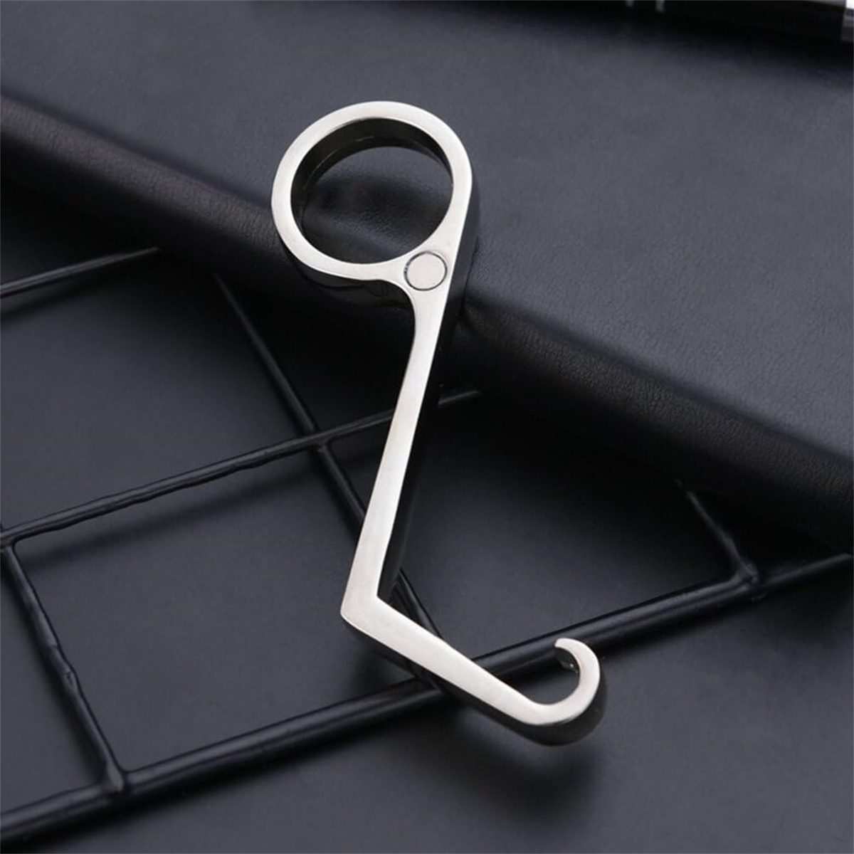 Silberner Metall-Schlüsselhalter auf schwarzer Oberfläche mit Metallgitter.