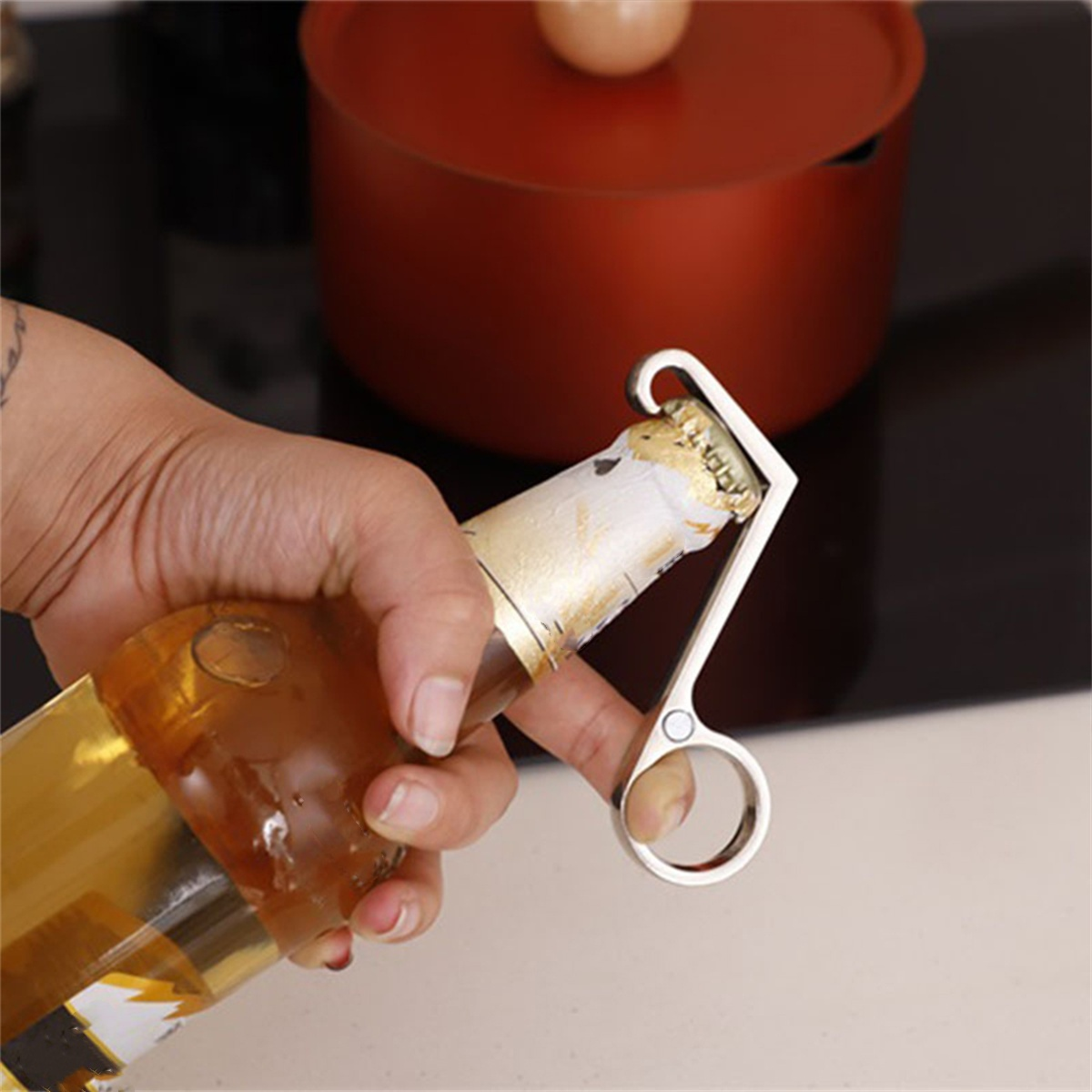 Eine Person, die einen Flaschenöffner benutzt, um eine Bierflasche zu öffnen. Die Flasche ist braun.