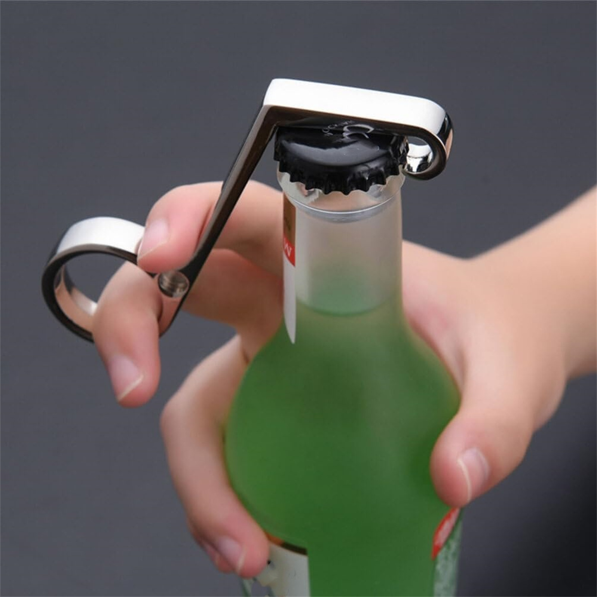 Person öffnet eine grüne Flasche mit einem silbernen Flaschenöffner.