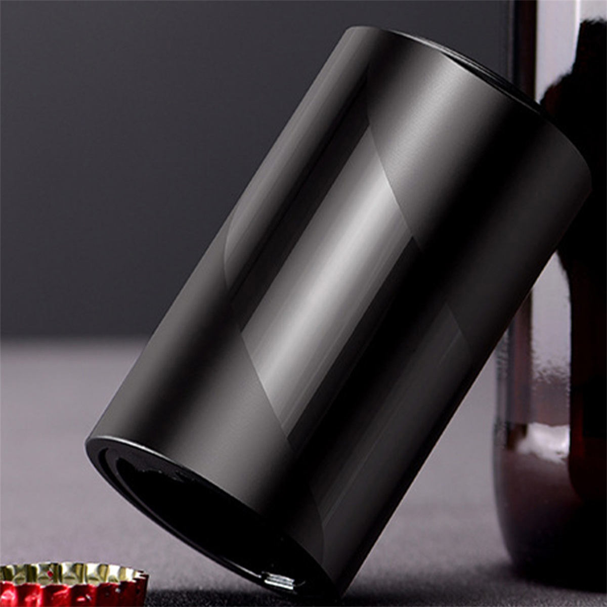 Schwarzer Flaschenöffner mit glänzendem Finish, abgewinkelt vor dunklem Hintergrund mit einer Flasche im Hintergrund.