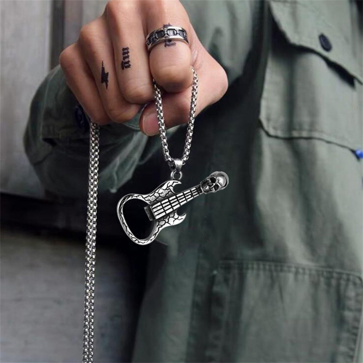 Die Hand einer Person, die eine gitarrenförmige Halskette an einer Kette trägt.